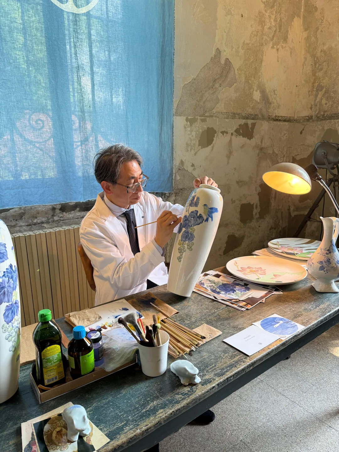 Artesão pintando vaso de cerâmica à mão durante o Fuorisalone 2026 em Milão