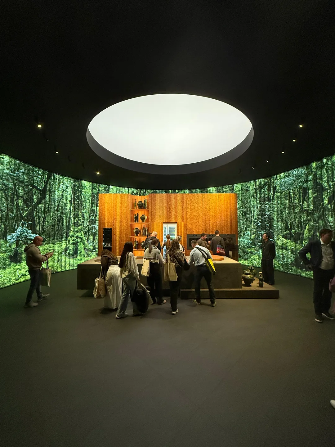 Instalação imersiva no Salone del Mobile 2026: cozinha em madeira cercada por projeções de floresta